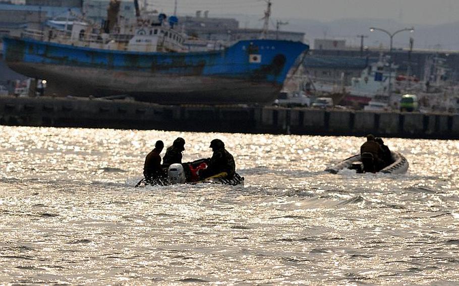 U.S. Navy divers are silhouetted as work in the Hachinohe City port on Friday, about 45 minutes south of Misawa Air Base, Japan. Sitting in the background is a giant boat that was beached and left where it sits when a 9-foot tsunami ripped through the port on March 11 after a record-setting Japanese earthquake.