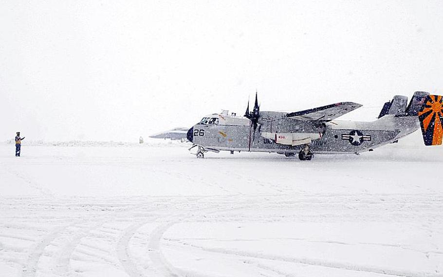 A sailor from Naval Air Facility Misawa - on Misawa Air Base, Japan - guides a C-2 passenger plane onto the ramp to disembark personnel during a heavy snow storm Saturday morning.