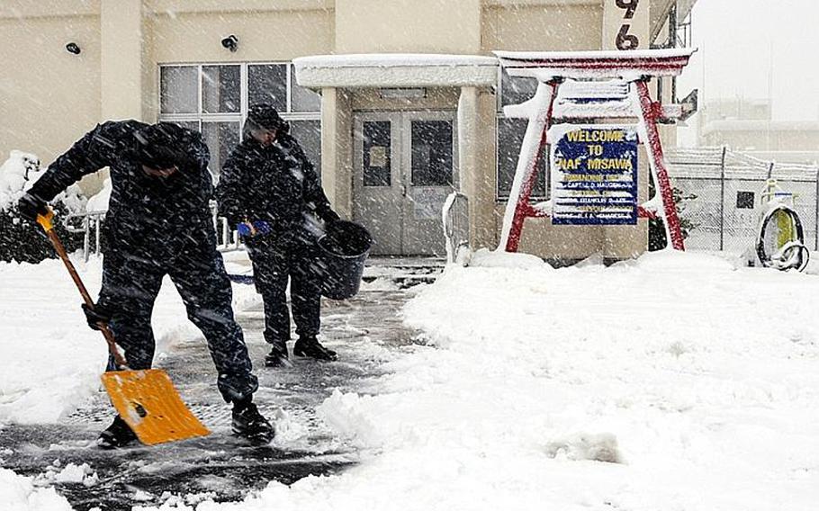 Sailors assigned to Naval Air Facility Misawa - on Misawa Air Base, Japan - clear a path on the sidewalk in front of the terminal during a heavy snow storm Saturday.