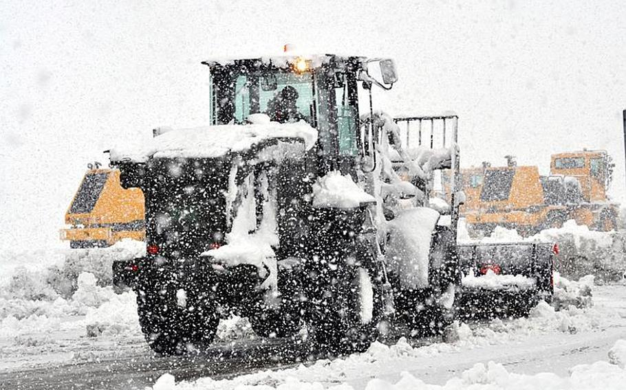 Workers plow snow on the taxi area on the flight line at Misawa Air Base, Japan, early Saturday morning during a heavy snow storm.