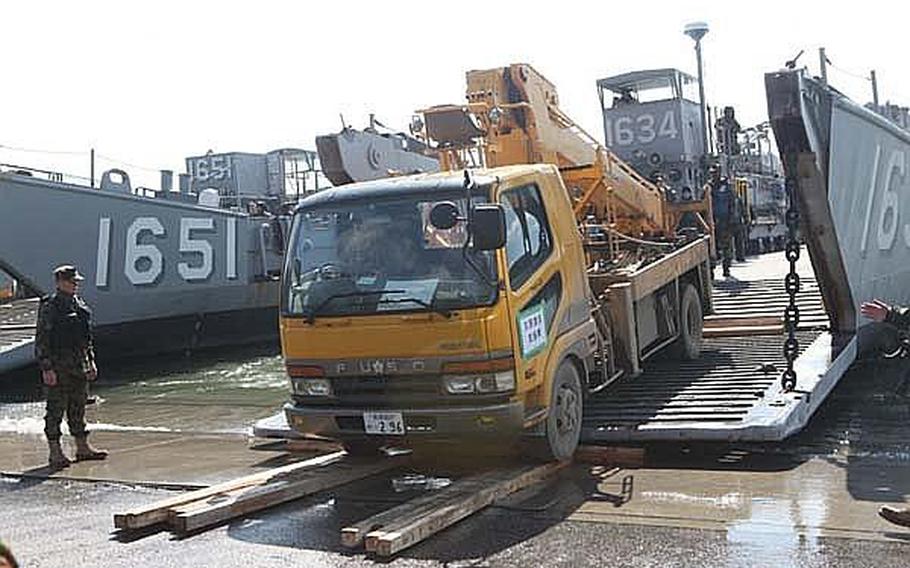 A utility truck is driven off a landing craft utility vehicle Sunday as part of a joint U.S. military/Japan Self-Defense Force effort to restore power to Oshima Island in Japan.