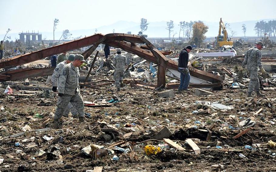Volunteers from Misawa Air Base, Japan, trudge through the debris field they had been tasked with cleaning Friday at Noda village, about a two-hour drive south of the base. Village officials thanked the volunteers for their work.