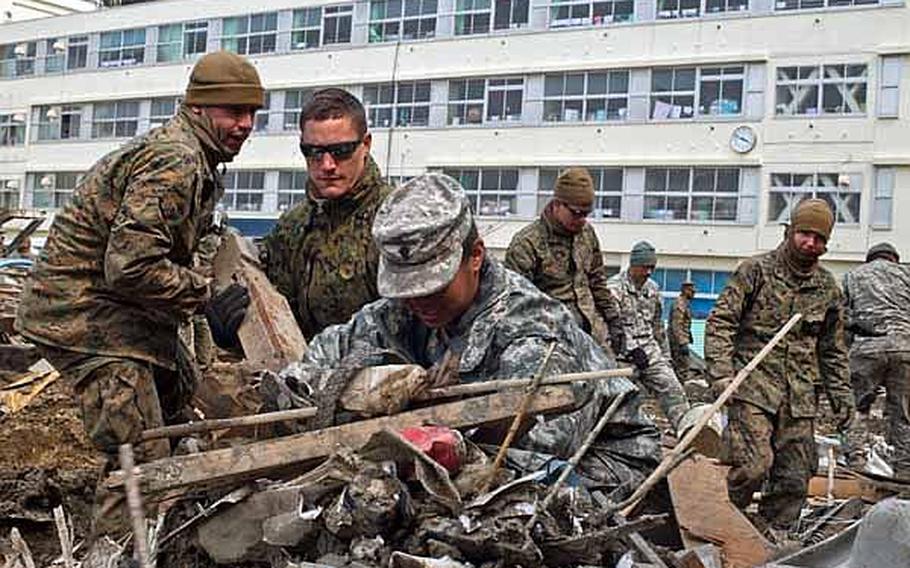 Spc. Christina Lee, 25, (right) and Lance Cpl. Dylan Messner, 20, along with other Marines and soldiers  from Okinawa, Camp Fuji and Camp Zama assist in the clean up of the Minato Elementary School in Ishinomaki, Japan, April 2, 2011.