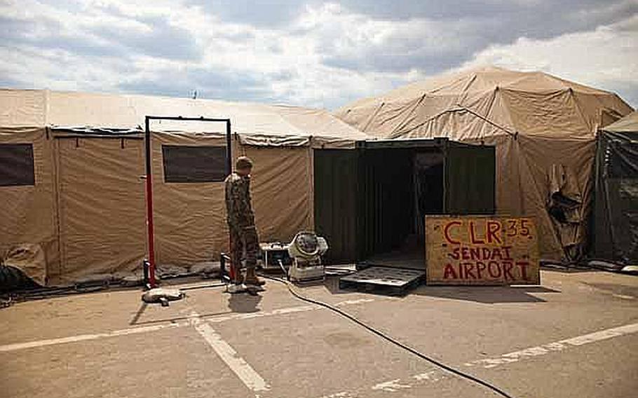 A Marine talks on the phone oustide the command operations center at the Sendai Airport in Sendai, Japan. The homemade wooden sign stands for Combat Logistics Regiment-35.