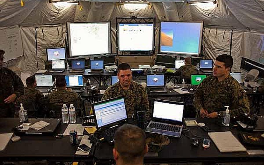 Marine Corps Staff Sgt. David Elbon, center, the arrival and departure air control group chief, talks with co-workers in the command and control center at the temporary U.S. military camp set up at the Sendai Airport in Sendai, Japan.