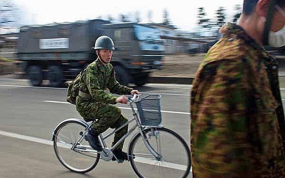 A soldier with the Japan Self-Defense Force rides his bicycle through a street at Camp Sendai, Japan.