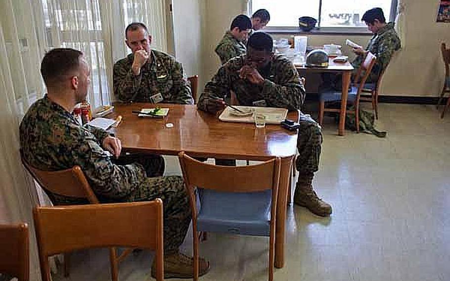 Three Marine Corps officers eat lunch at a diner at Camp Sendai, Japan as Japan Self Defense Force troops read manga after finishing their meals. 