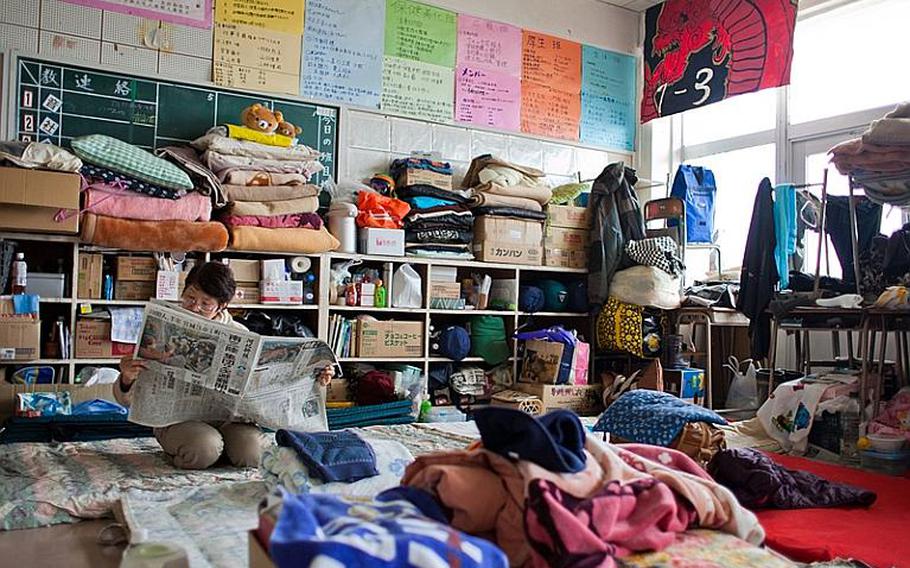 A displaced resident of the Kadonowaki Middle School shelter reads the newspaper after lunch.