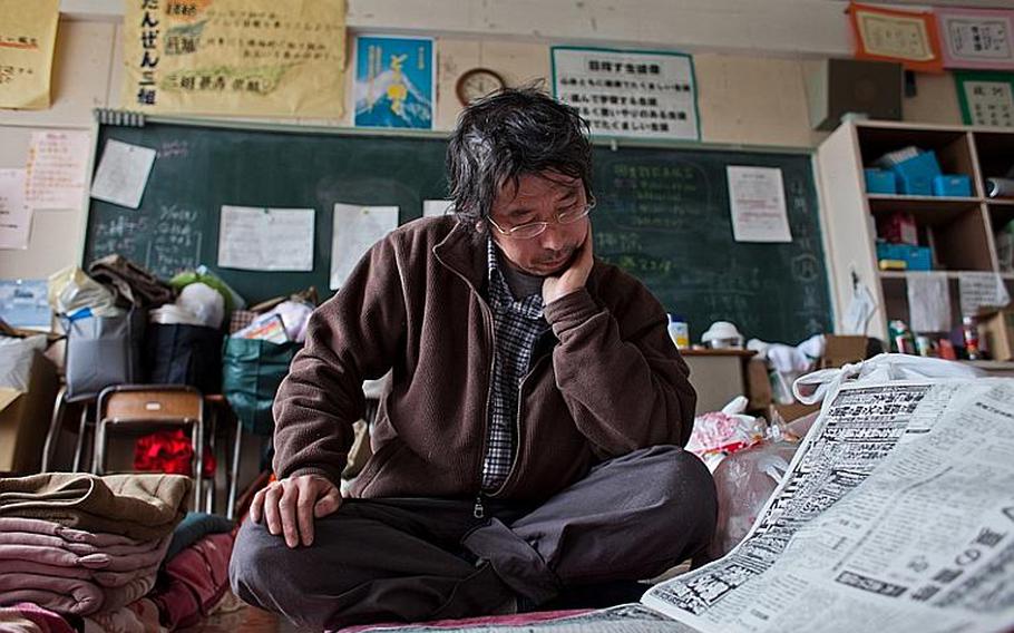 Hidetoshi Oikawa, a dental technician whose home and place of work were destroyed in the March 11 tsunami, reads a newspaper at the Kadonowaki Middle School shelter in Ishinomaki, Japan.
