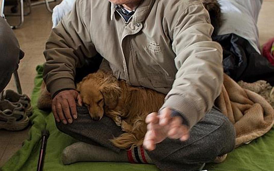 Koichi Matsumoto sits with his dog, Jonko, at the Kadonowaki Middle School shelter in Ishinomaki, Japan. He has applied to live in one of the emergency homes constructed by the government, but said the number of homes is inadequate.