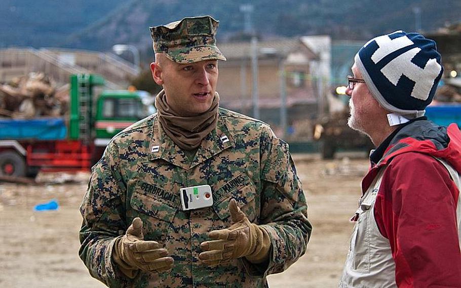 Marine Corps Capt. Robert Gerbracht and Darren Polischuk, a Canadian worker with the Christian relief organization Samaritan's Purse chat after Marines helped deliver boxes of aid that Samaritan's Purse had provided to the displaced residents of the Watanoha Elementary School shelter in Ishinomaki, Japan. The U.S. military has been coordinating with other NGOs to deliver aid.