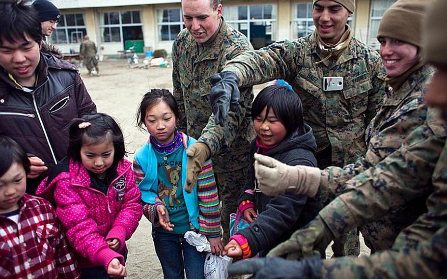 Marines from Okinawa and Camp Fuji play the game "rock, paper, scissors" with children at the Watanoha Elementary School shelter in Ishinomaki, Japan after assiting to clean up the school grounds as well as to deliver aid provided by the Christian relief organization Samaritan&#39;s Purse. The U.S. military has also been coordinating with other NGOs to deliver aid, officials said.