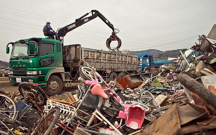 A city worker moves heaps of bikes and other scrap metal into a truck at one of two temporary tsunami-related trash dump sites in Ishinomaki, Japan.