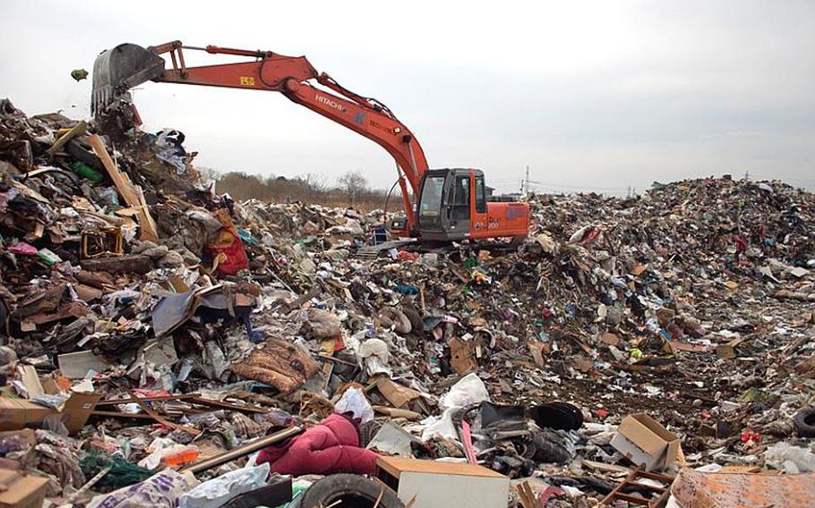 City workers consolidate mounds of trash to create room for more at one of two temporary tsunami-related trash dump sites in Ishinomaki, Japan.