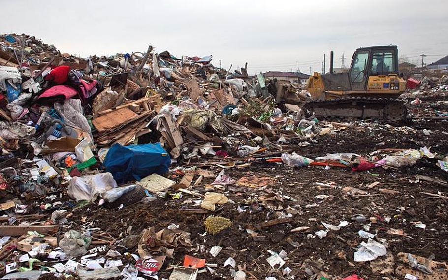 A bulldozer moves to consolidate scattered garbage at one of two massive dump sites set up to store tsunami-related trash in Ishinomaki, Japan.