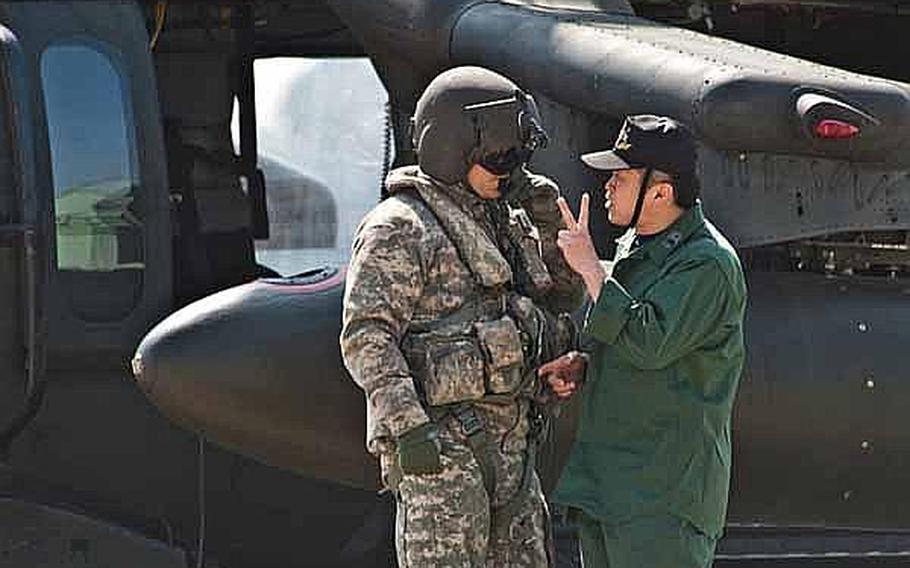 A UH-60 Black Hawk crew member, left, talks with the ground crew at Japan Self-Defense Force's Matsushima Air Base in Higashimatsushima, Japan. Two UH-60s from Camp Zama-based U.S. Army Aviation Detachment Japan, along with two fixed-wing aircraft from Naval Air Facility Atsugi, have transported personnel and supplies in support of relief efforts in the region since March 18.