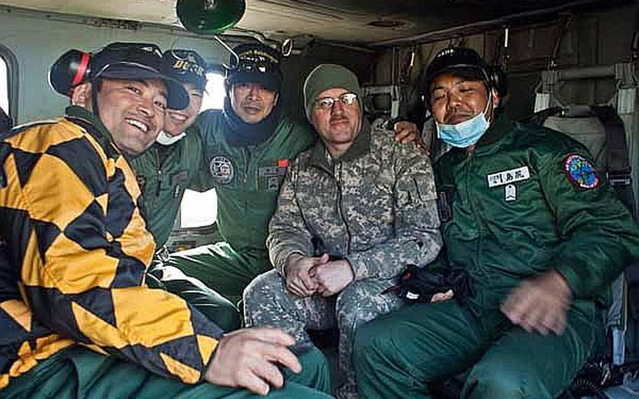 Sgt. 1st Class Scott Newhart, crew chief of a U.S. Army Aviation Detachment UH-60 Blackhawk helicopter, poses for a photo with Japan Self-Defense Force troops at Matsushima Air Base in Higashimatsushima, Japan. Two of the detachment&#39;s blackhawks along with two fixed wing aircraft have been used to transport personnel and supplies in support of relief efforts.