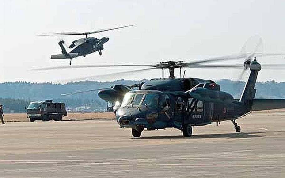 One Japan Self-Defense Force helicopter lands as another taxis at Matsushima Air Base in Higashi Matsushima, Japan. Two U.S. Army Aviation Detachment Japan Black Hawk helicopters, along with two-fixed wing aircraft from Naval Air Facility Atsugi, are helping the JSDF transport personnel in support of relief efforts.