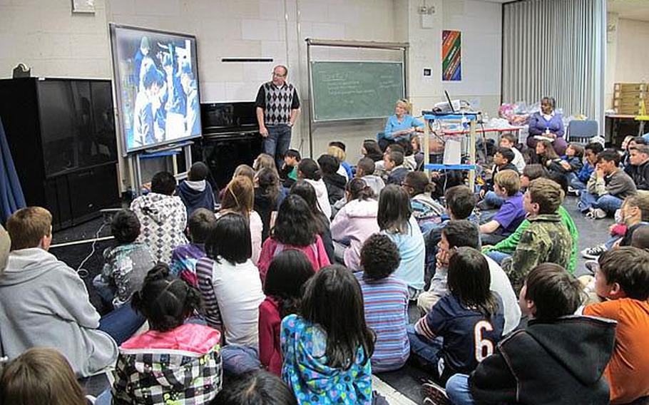 Bill Hunter, standing, shows students at Yokosuka Naval Base in Japan pictures from his recent relief work in the tsunami- and earthquake-ravaged areas near Sendai. Educators at base schools in Japan say they must walk a fine line by teaching students about the disaster, but not increasing their anxieties.