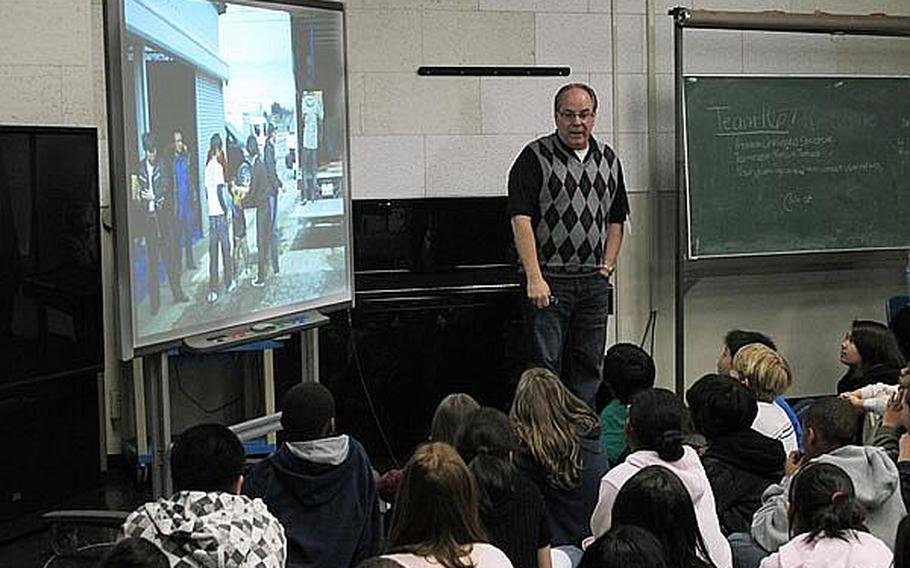 Bill Hunter, standing, shows students at Yokosuka Naval Base in Japan pictures from his recent relief work in the tsunami- and earthquake-ravaged areas near Sendai. Educators at base schools in Japan say they must walk a fine line by teaching students about the disaster, but not increasing their anxieties.