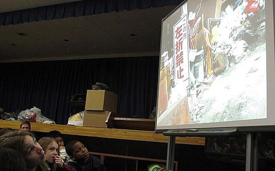 Fourth grade and fifth grade students at Yokosuka Naval Base's Sullivans School in Japan view photos taken by a local teacher recently of the damage wrought by the March 11 earthquake and tsunami near Sendai. Educators at base schools in Japan say they must walk a fine line by teaching students about the disaster, but not increasing their anxieties.