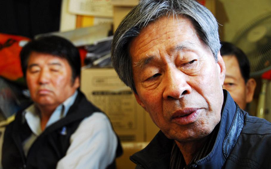 Jon Chon-bong, 78, sits inside a small building near the entrance of Wolmi Park and talks about the U.S. bombing of hs village on Wolmi Island in 1950. He is one of 44 South Koreans who filed a lawsuit earlier this year seeking compensation for the property their families lost in the bombing. Members of the group take turns sleeping in the building in hopes of attracting attention to their request. Behind him, left, is Jeong Ji-eun, whose father died in the attack.