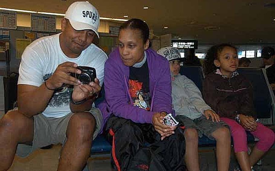 Miguel Rodriguez, 40, left, shows videos of a San Antonio Spurs basketball game to his wife, Army Spc. Tina Johnson, 37, while their daughter, Leilani, 7, and son, Nehemiah, 10, wait for a bus at Narita Airport, Japan, on Friday. Thousands of family members, who left Japan following the March 11 earthquake are now returning.