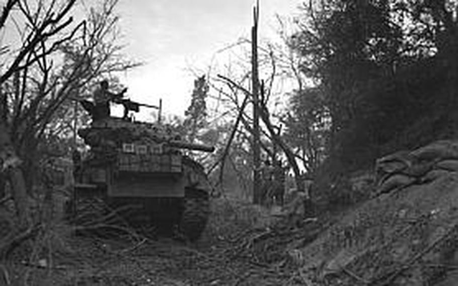 Tank-led U.S. Marines accept the surrender of the enemy on Wolmi Island as the tank commander points out another pillbox.