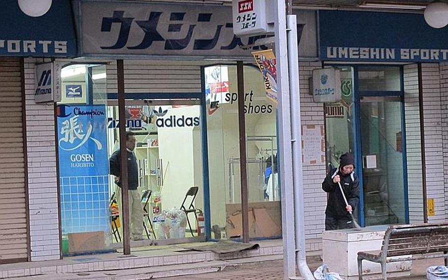 A woman sweeps up outside a re-opening store in Ishinomaki, where thousands perished in the 55-foot tsunami that struck following the March 11 earthquake. A mile or two from total devastation, a few businesses near the city&#39;s train station are trying to regain some sense of normalcy.