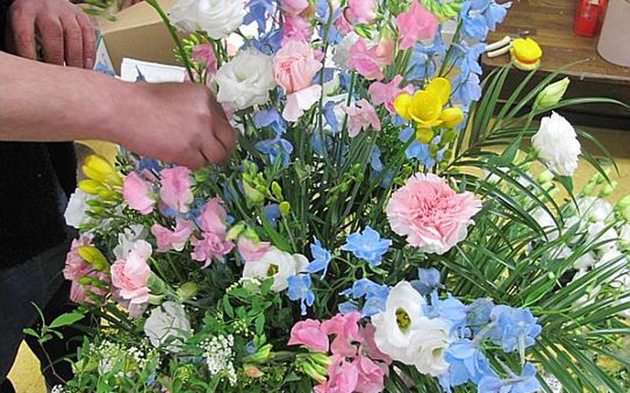 Hiroshi Shibata arranges flowers out of a temporary shop near Ishinomaki Station on Friday. Shibata&#39;s original shop was damaged beyond use in Ishinomaki, where thousands perished in the 55-foot tsunami that struck following the March 11 earthquake. Shibata&#39;s business is one of the few to reopen near the station, which is just a mile or two from total devastation.