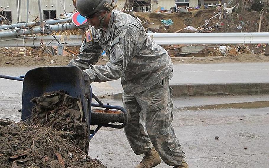 Cpl. Jorge Alaniz dumps another pile of dirt shoveled from Nobiru train station during one of dozens of wheelbarrow trips he made Friday. A 42-soldier combined unit from both Camp Zama and Okinawa completed the cleanup at Nobiru and had finished clearing another station by Monday.