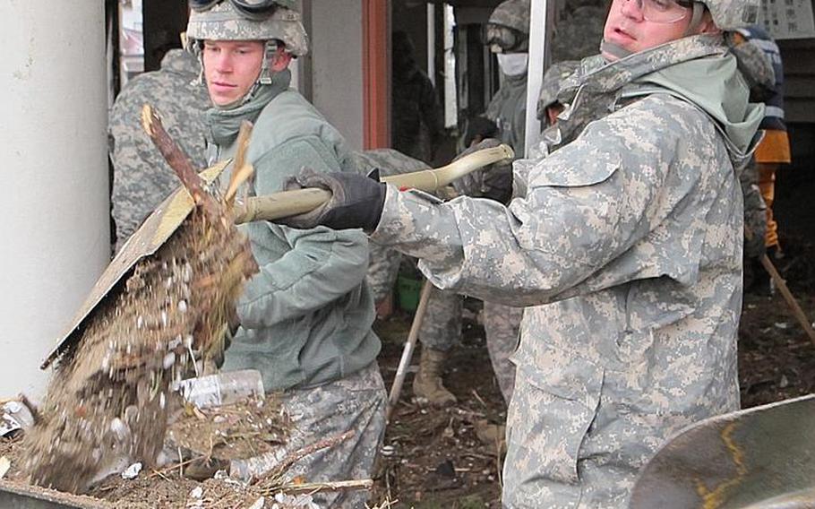 Spc. Timothy Jones, left, and Spc. Ivan Santos shovel dirt and debris while clearing out Nobiru train station on Friday, in Japan's tsunami-battered northeast. A 42-soldier combined unit from both Camp Zama and Okinawa completed the cleanup at Nobiru and had finished clearing another station by Monday.