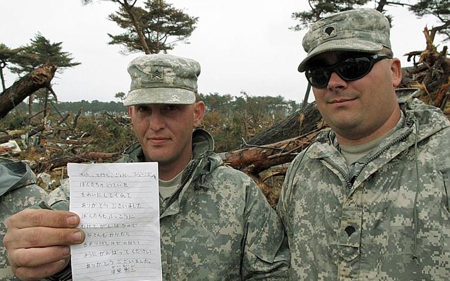 Sgt. Joshua Mason, left, displays a thank-you note he received after he and his unit of 42 soldiers cleaned up a school in tsunami-ravaged northeast Japan recently. The appreciation has meant a lot to soldiers like Mason, who have been clearing train stations of muck and debris since Thursday.
