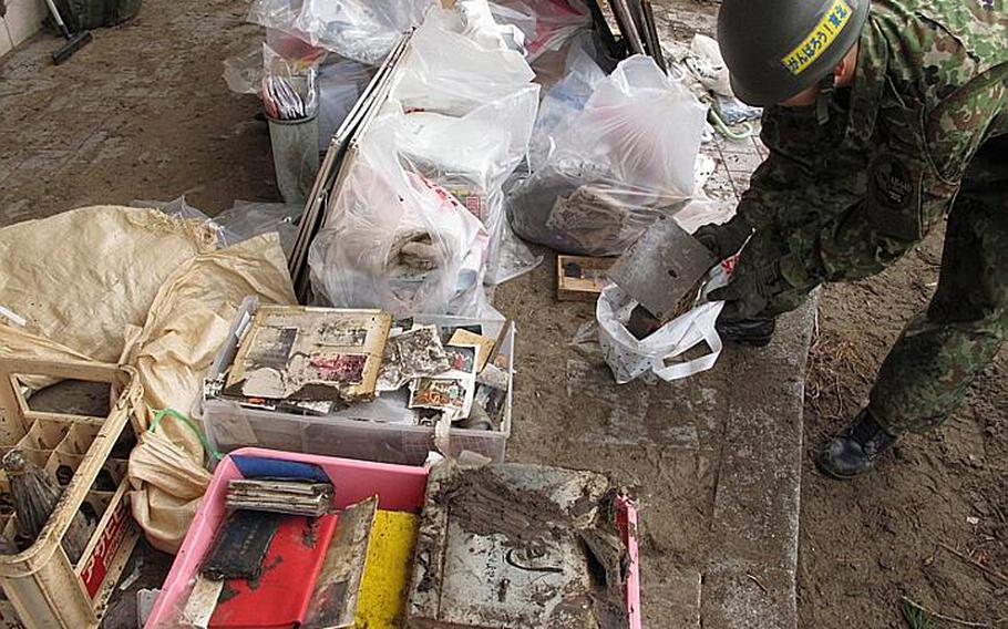 A Japanese Self-Defense Force soldier bags salvageable items during a cleanup at Nobiru Station on Friday. The small contingent of Japanese joined a 42 U.S. soldiers from both Camp Zama and Okinawa to complete the train station&#39;s cleanup.