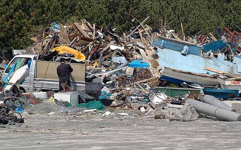 A Japanese man loads tsunami debris into his truck Tuesday at the Misawa City port. A March 11 tsunami gutted the port, washing out roads, destroying buildings and killing two residents.