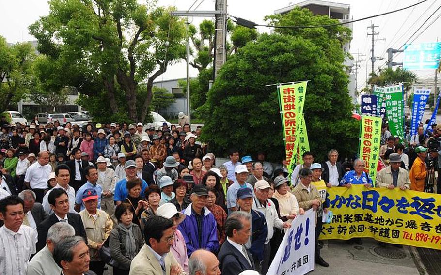 Hundreds of Okinawans rally Thursday in front of Okinawa City branch of the Naha District Court, prior to filing a lawsuit against the Japanese government over aircraft noise from Kadena Air Base.