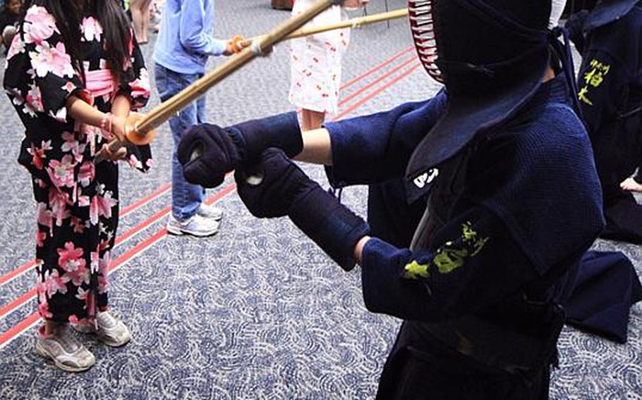 Rio Karr, an 8-year-old at Joan K. Mendel Elementary School learns the how to weirld a Kendo stick from students at Kashiwagi  High School in Kanagawa Prefecture on Tuesday, as part of the Japan-Asia Day activities at the school.