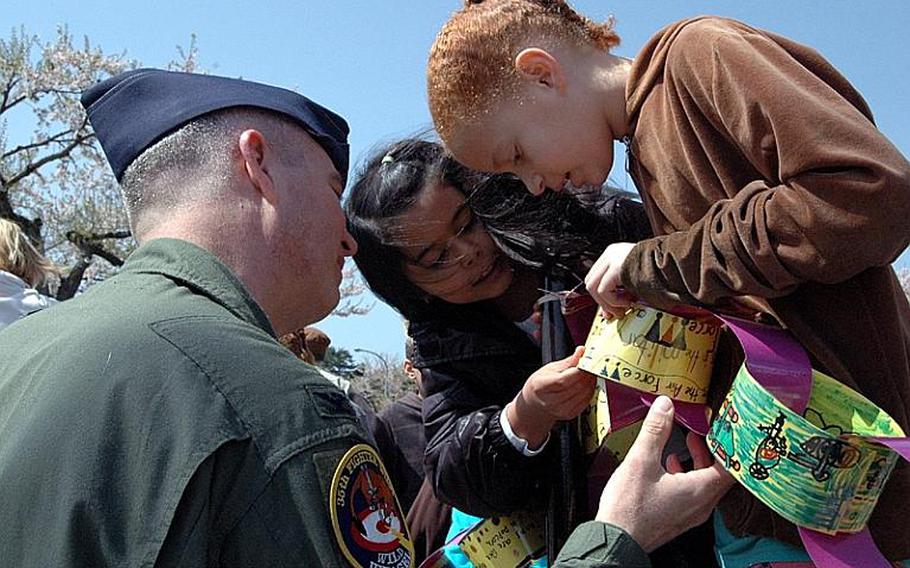 Cummings Elementary School third-graders Kaia Fleming, right, and Danielle Goodyear show Col. Van Wimmer Jr. the links they made to celebrate the DOD's Month of the Military Child during a ceremony Friday at Misawa Air Base, Japan. The annual celebration is meant to spotlight the role those children play in their local communities.