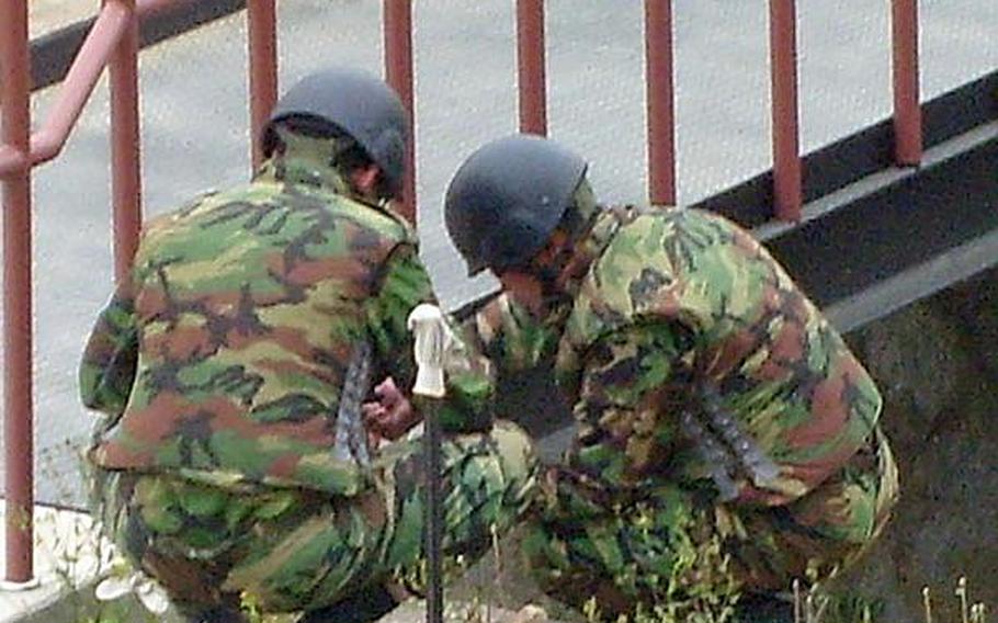 South Korean explosive ordnance technicians work to secure a Korean War-era grenade found at Camp Carroll on Friday morning.