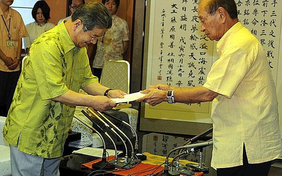 Okinawa Governor Hirokazu Nakaima, right, hands Japanese Defense Minister Toshimi Kitazawa a list of written requests to include the early closure of Marine Corps Air Station Futenma during a meeting at the Prefectural Government Office in Naha on Saturday.