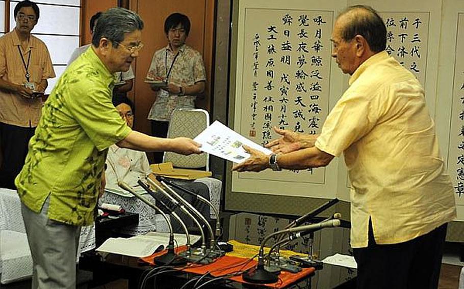 Japanese Defense Minister Toshimi Kitazawa, left, hands a brochure to Okinawa Governor Hirokazu Nakaima during a meeting in which Kitazawa sought the governor?s support in moving Futenma air operations to Camp Schwab. The brochure contained reasons for the Marine Corps air station to remain on Okinawa.
