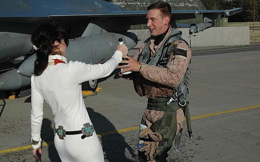 Natalee Kotowski hands her husband, Capt. Scott Kotowski, a bottle of champagne after spraying him with it upon his return to Misawa Air Base, Japan, from Iraq on Friday. 