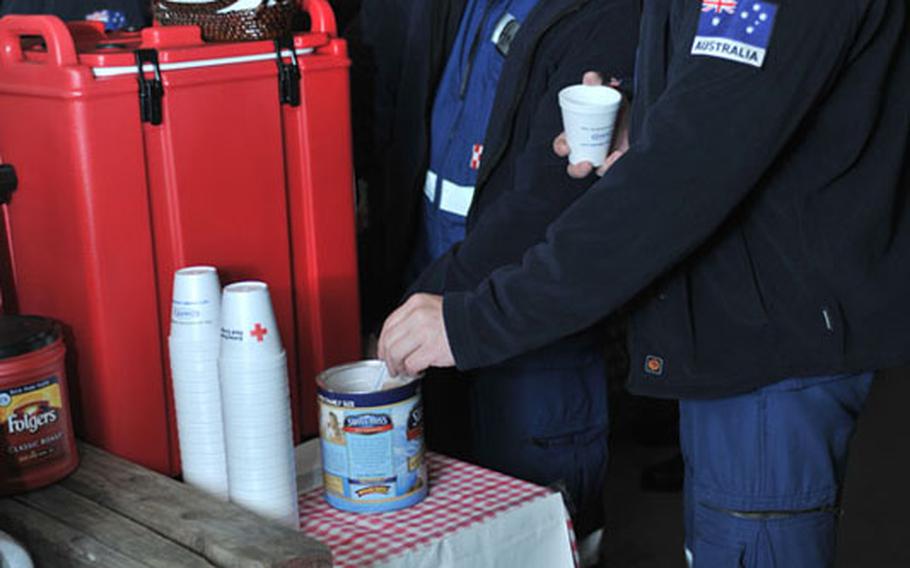 Members of the Queenland Urban Search and Rescue Taskforce partake in the refreshments provided by the American Red Cross at Yokota Air Base, Japan, on March 14. The Red Cross volunteers manned a canteen 24 hours a day for inbound forces.