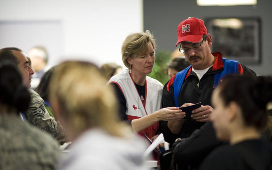 Two Red Cross volunteers review a passport during a large-scale outprocessing of military dependents at Yokota Air Base, Japan, on March 19. 