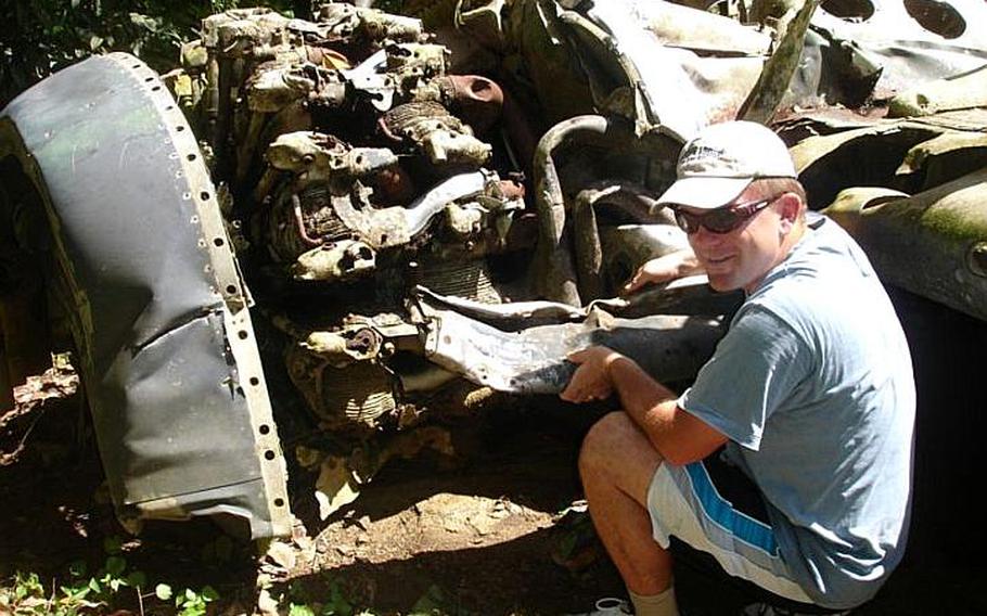 Pat Ranfranz  crouches next to the wreckage from an old U.S. Navy FSF shipboard fighter plane he helped to discover in 2006 on  Yap Island during his search ifor the crash site of his uncle&#39;s long lost  B-24J bomber.