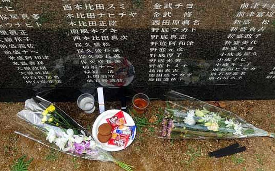 Food, drinks, and flowers rest at the base of one of the many granite walls etched with the names of all who died during the Battle of Okinawa.