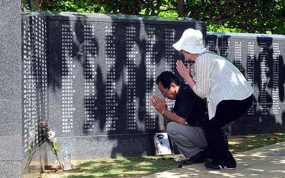 A man and woman bow their heads and offer a few minutes of prayer for a loved one who died in the Battle of Okinawa.