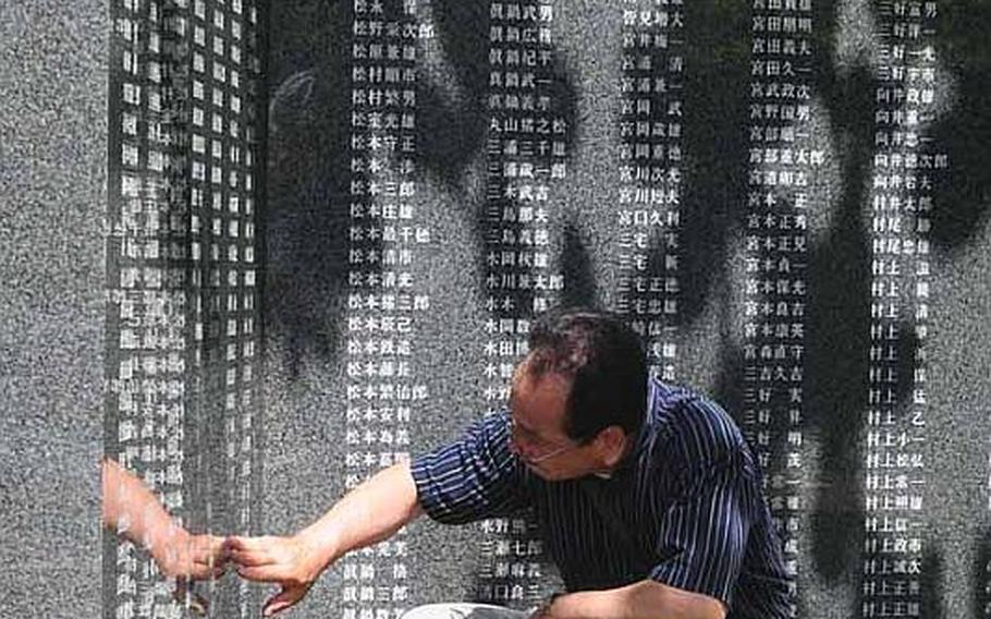 A man touches name of a loved one at a memorial of the Battle of Okiwana. There are more than 240,000 names etched into the large granite walls.