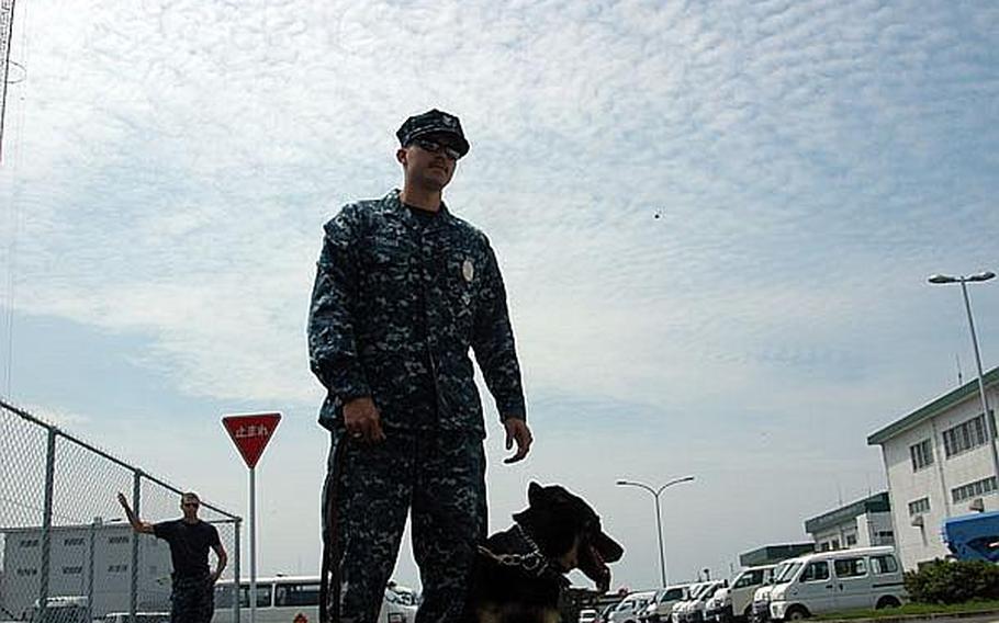 Petty Officer 2nd Class Kojiro Thomas and his military working dog, Asta, train at Sasebo Naval Base. Seaman Alex Monce observes.