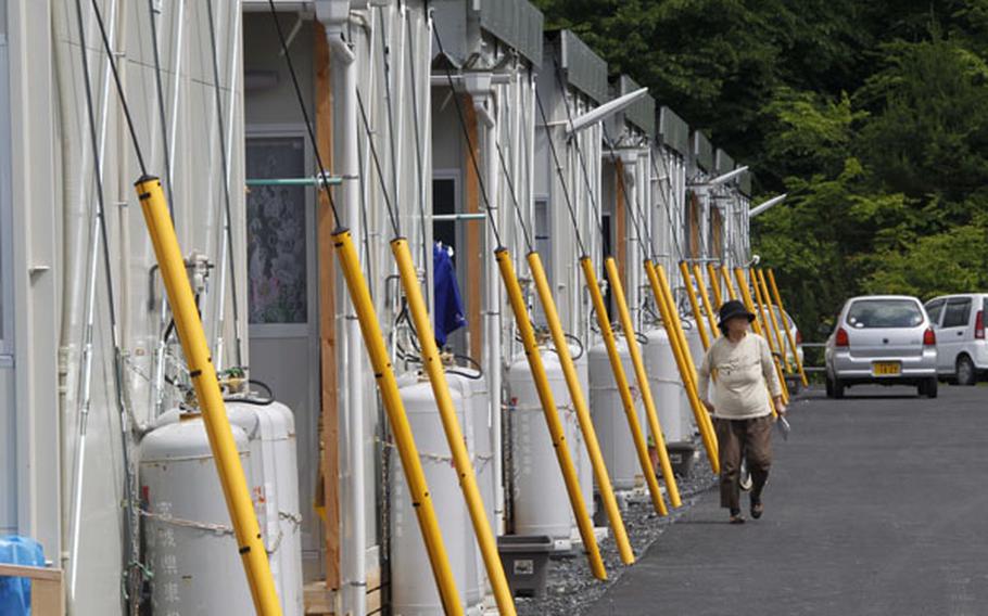 A woman walks by the rows of temporary housings for the March 11 earthquake and tsunami survivors at Hibiki Industrial Park in Higashimatsushima, Miyagi Prefecture, northeastern Japan, June 14.